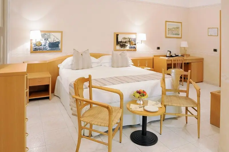 Chambre lumineuse avec un grand lit et un coin salon.