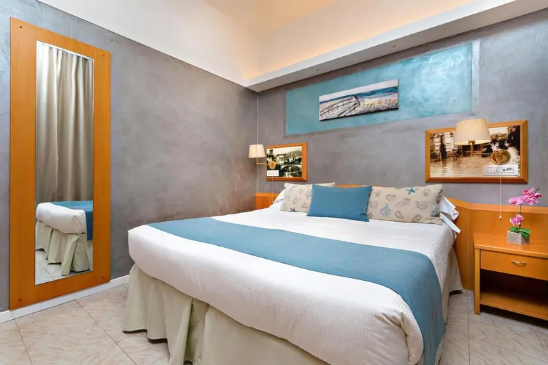 Une chambre lumineuse avec un grand lit recouvert d'une courtepointe bleue et turquoise.