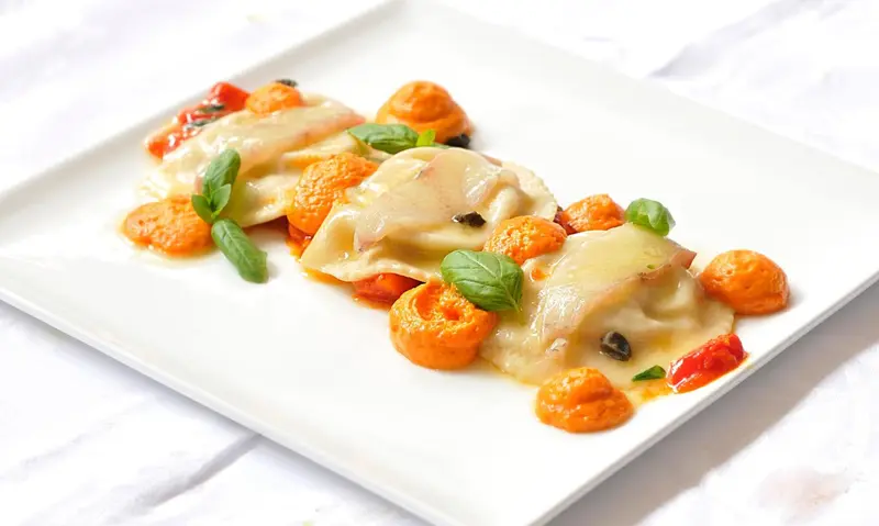 Assiette de raviolis à la sauce crémeuse et aux tomates cerises.