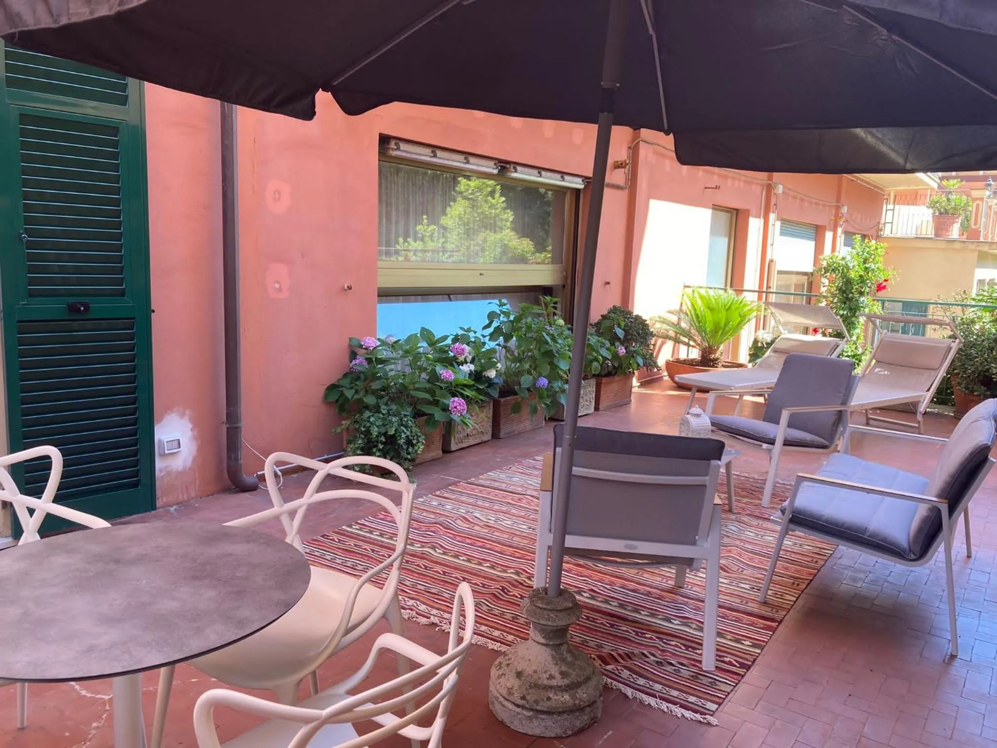 Terrasse ombragée avec mobilier de jardin et plantes fleuries.