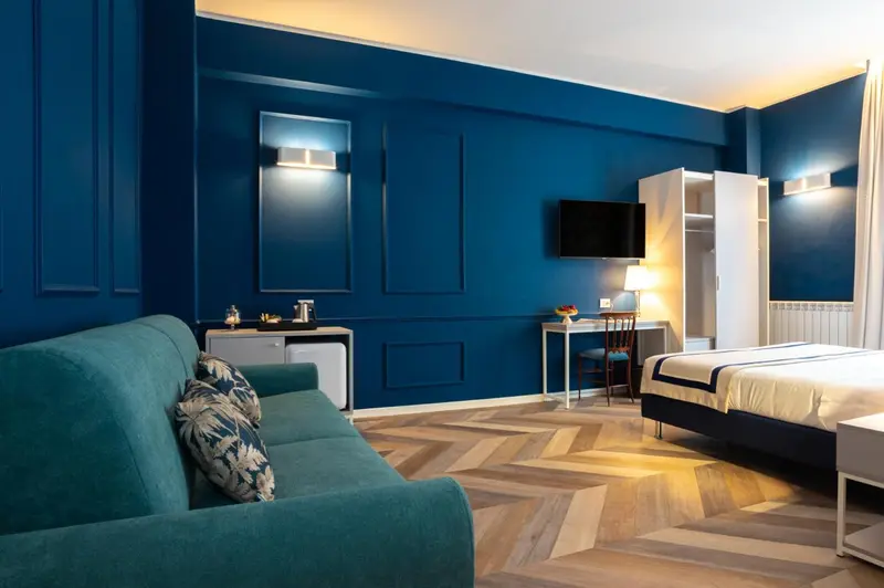 Une chambre lumineuse avec un canapé vert et un lit recouvert d'une courtepointe.