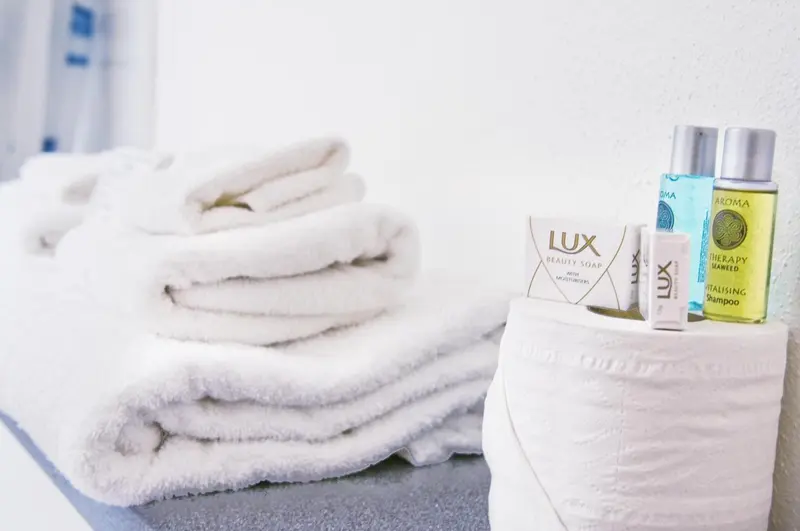 Serviettes blanches pliées et produits de toilette sur un plan de travail.
