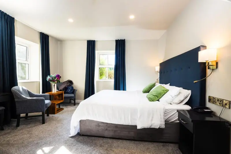 Une chambre lumineuse avec un grand lit et un fauteuil.