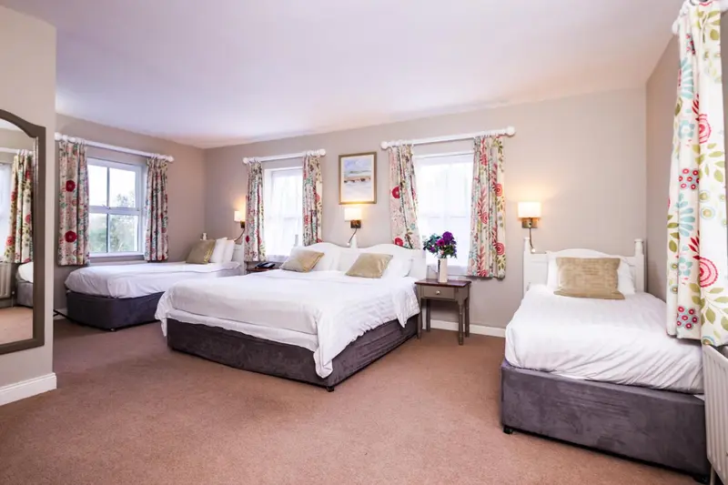 Chambre spacieuse avec trois lits et décoration florale.