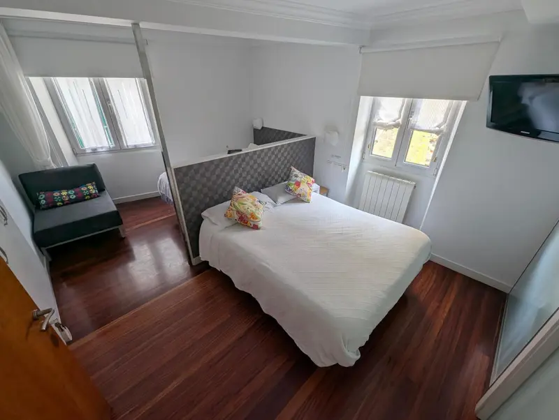 Une chambre lumineuse avec un lit double et un canapé convertible.