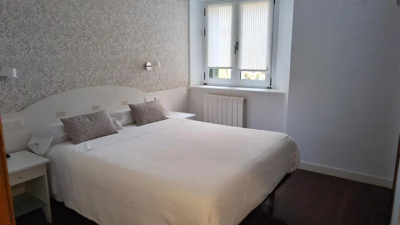 Une chambre lumineuse avec un lit double et une fenêtre.