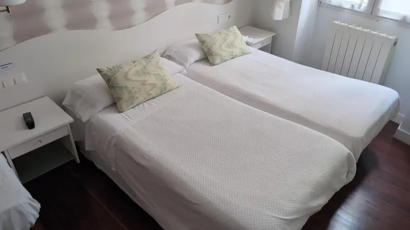 Une chambre lumineuse avec deux lits simples et une décoration sobre.