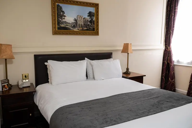 Une chambre avec un grand lit recouvert d'une courtepointe et de coussins blancs.