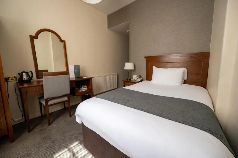Une chambre d'hôtel lumineuse avec un lit et un coin bureau.