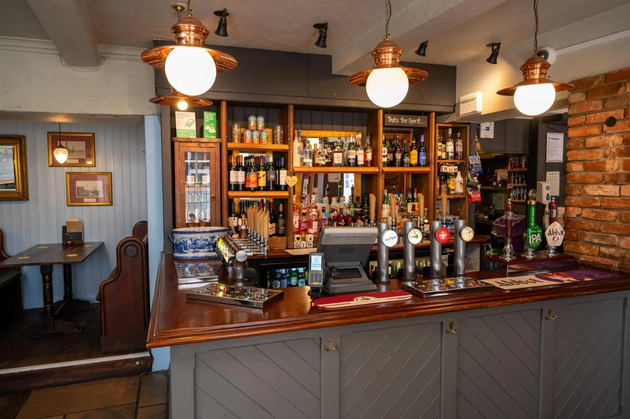 Un comptoir de bar en bois sombre avec des bouteilles et des verres.