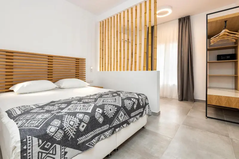 Une chambre lumineuse avec un grand lit recouvert d'une couverture à motifs.