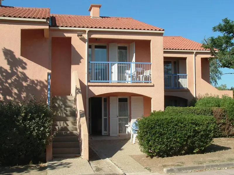 Façade d'un bâtiment rose avec des balcons et des volets.