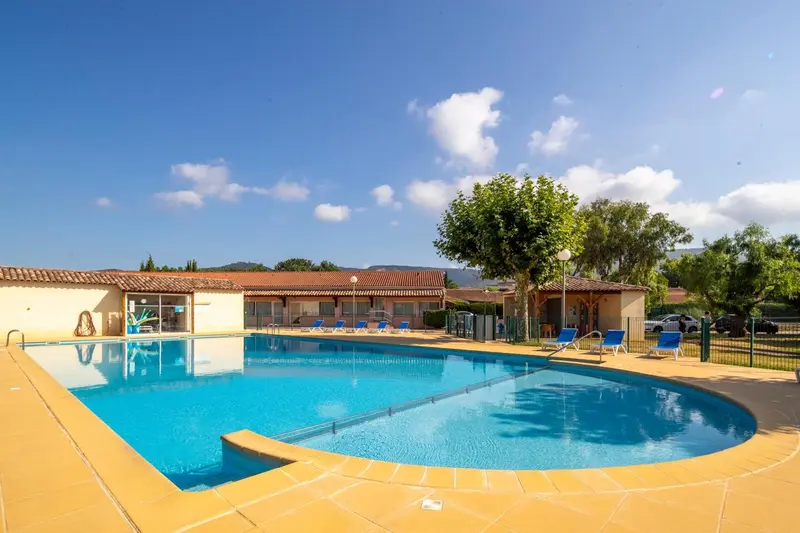Une piscine rectangulaire avec une terrasse ensoleillée et des transats.