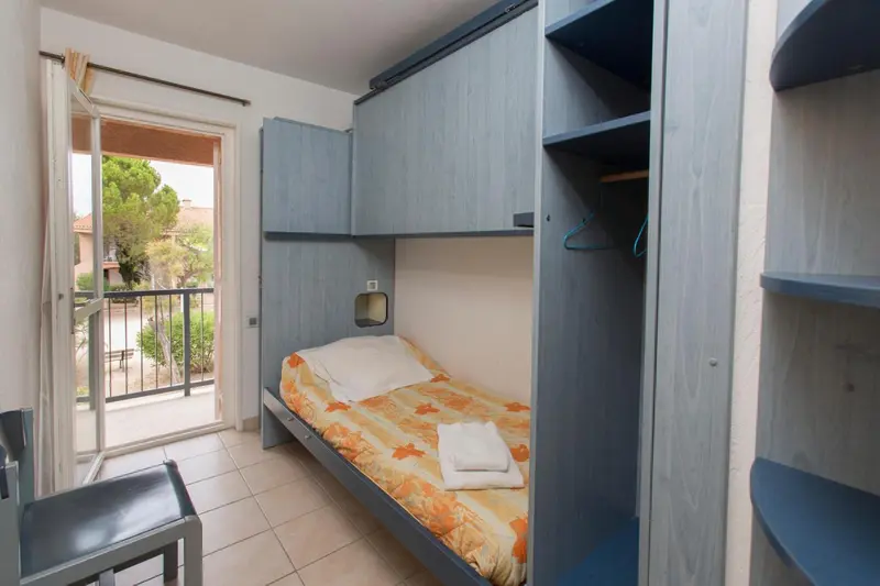 Une chambre avec un lit simple et un accès à une terrasse.