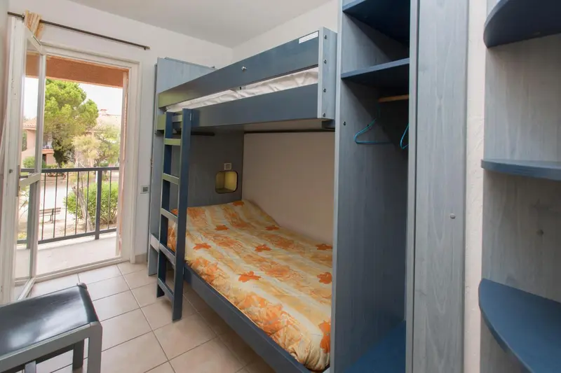 Une chambre avec un lit superposé et une vue sur un jardin.