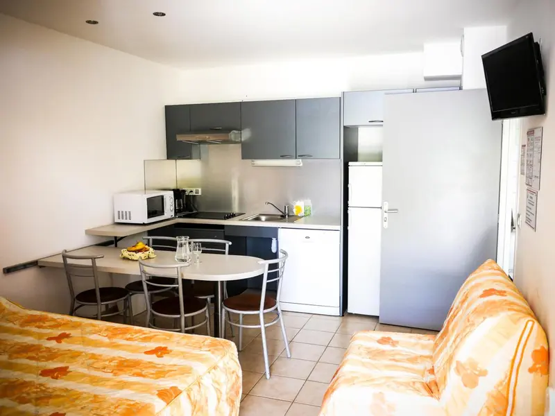 Une kitchenette équipée avec un coin repas et un canapé.