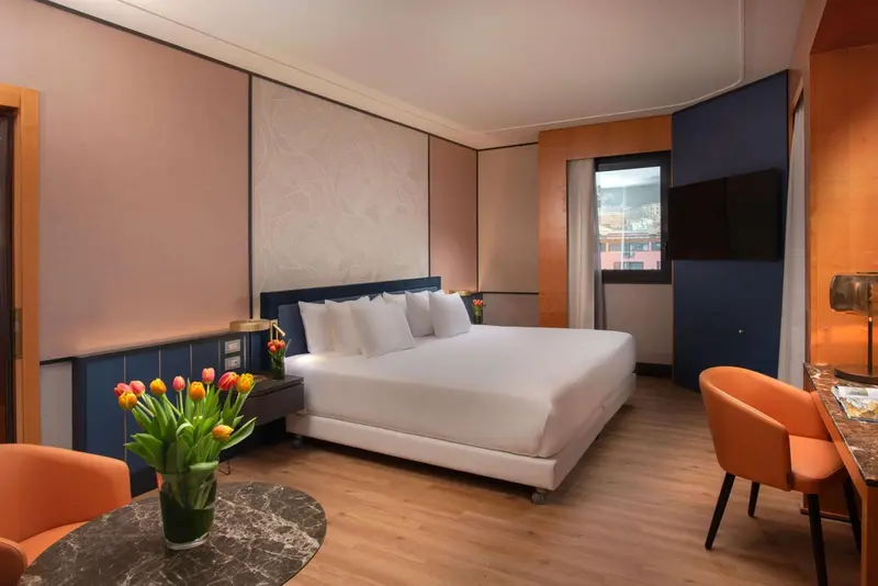 Une chambre lumineuse avec un grand lit et un bureau.