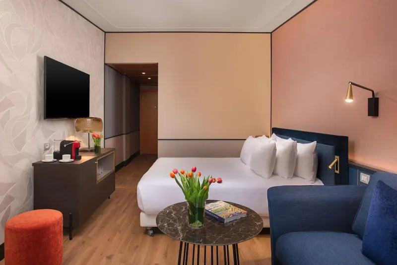 Une chambre lumineuse avec un grand lit et un coin salon.