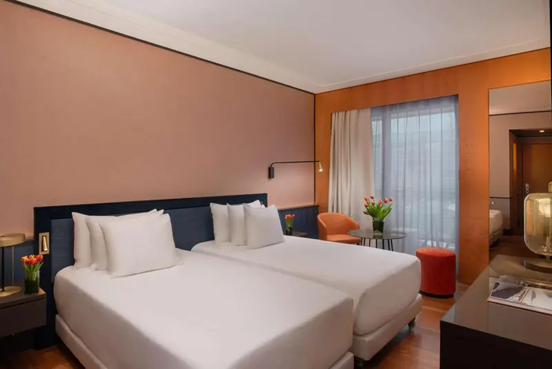 Une chambre lumineuse avec un grand lit et un fauteuil.