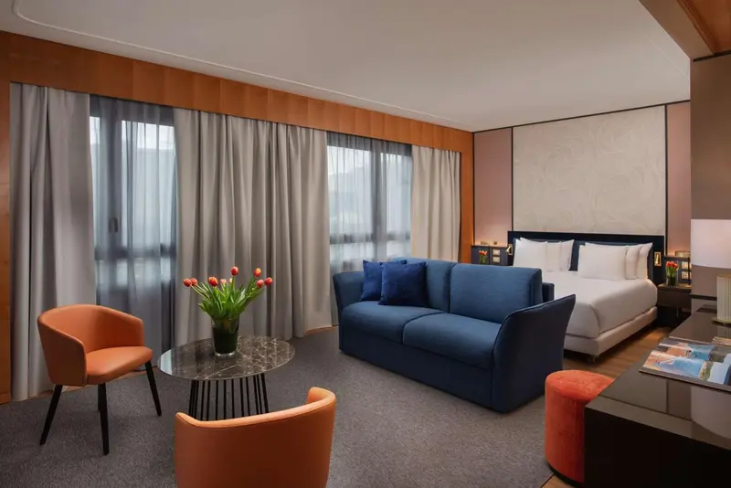 Espace de vie intérieur avec canapé, fauteuils et lit.