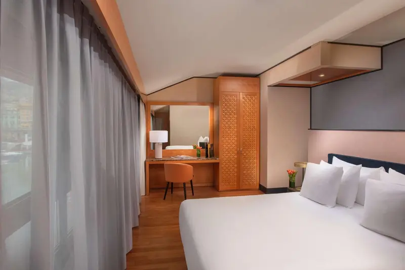 Une chambre lumineuse avec un lit blanc et un bureau en bois.