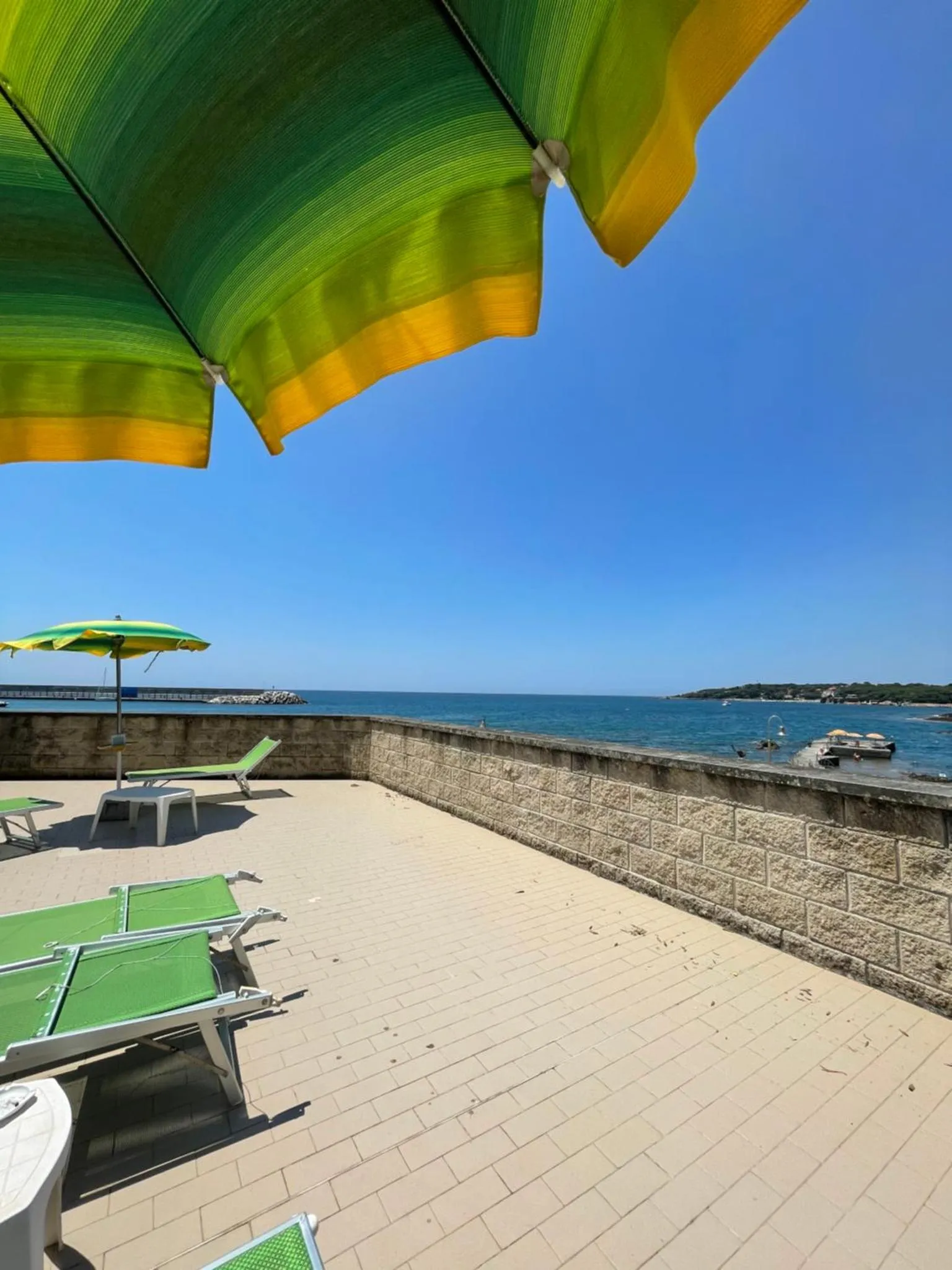 Terrasse ensoleillée avec transats et vue sur la mer.