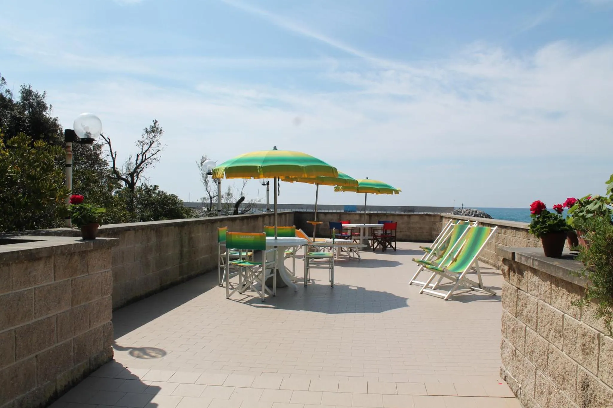 Terrasse ensoleillée avec mobilier de jardin et vue sur la mer.