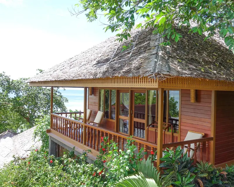 Une terrasse en bois donne sur la mer depuis un bungalow surélevé.
