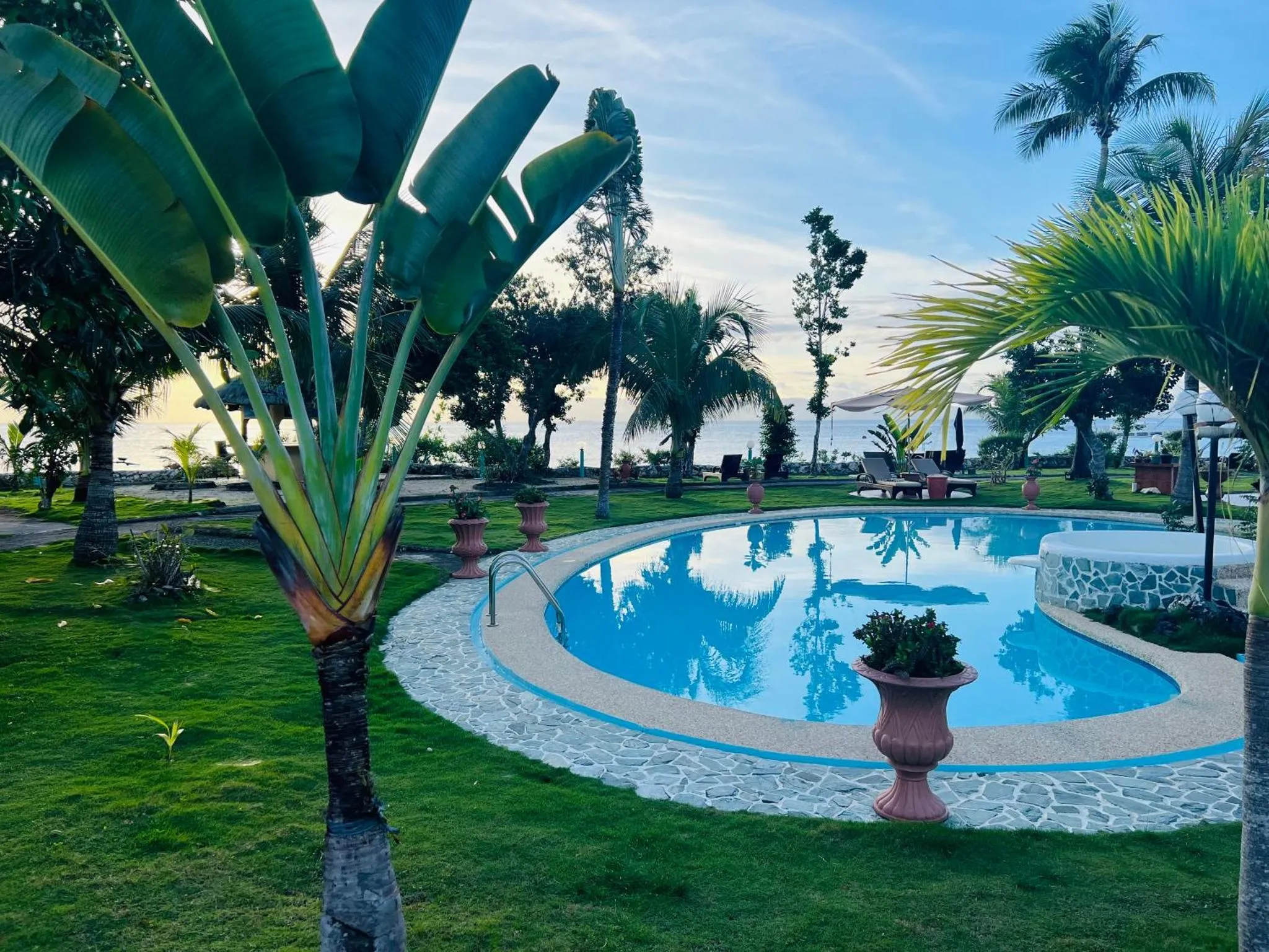 Une piscine bordée de verdure avec une vue sur la mer au loin.
