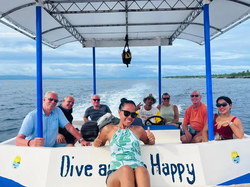 Un groupe de personnes souriantes est assis sur un bateau en mer.