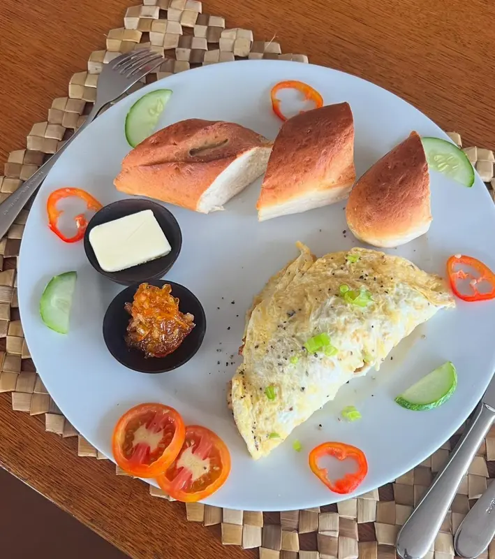 Assiette de petit-déjeuner avec omelette, pain et confiture.