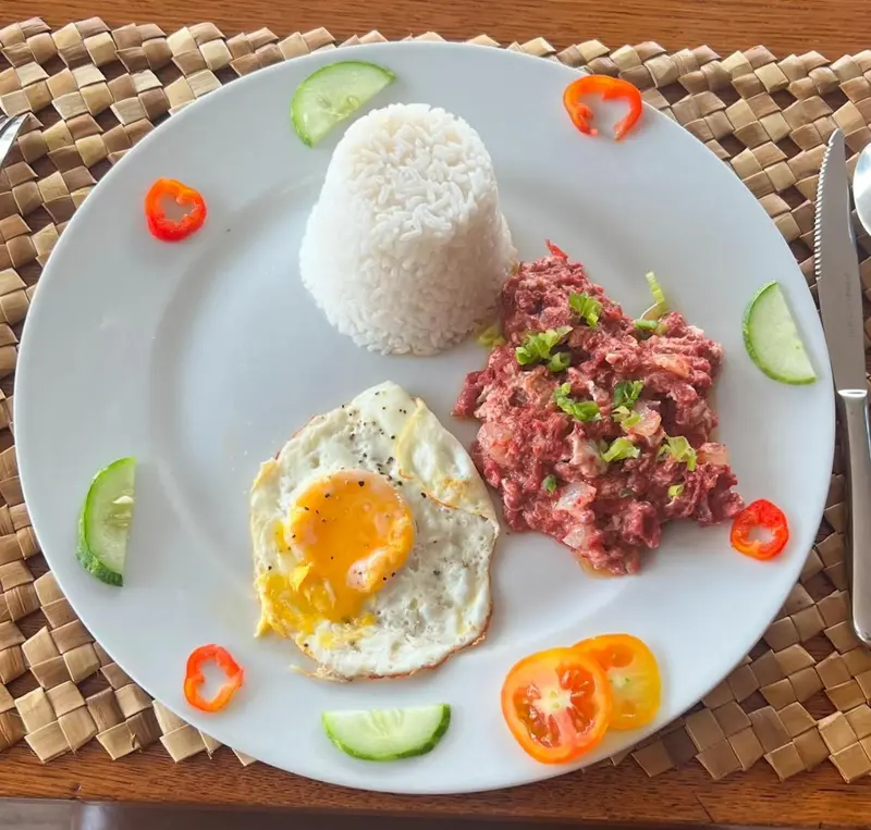 Assiette de riz blanc, d'œuf au plat et d'une préparation à base de viande hachée, décorée de légumes.