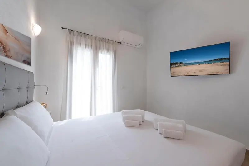 Une chambre lumineuse avec un grand lit et une télévision murale.