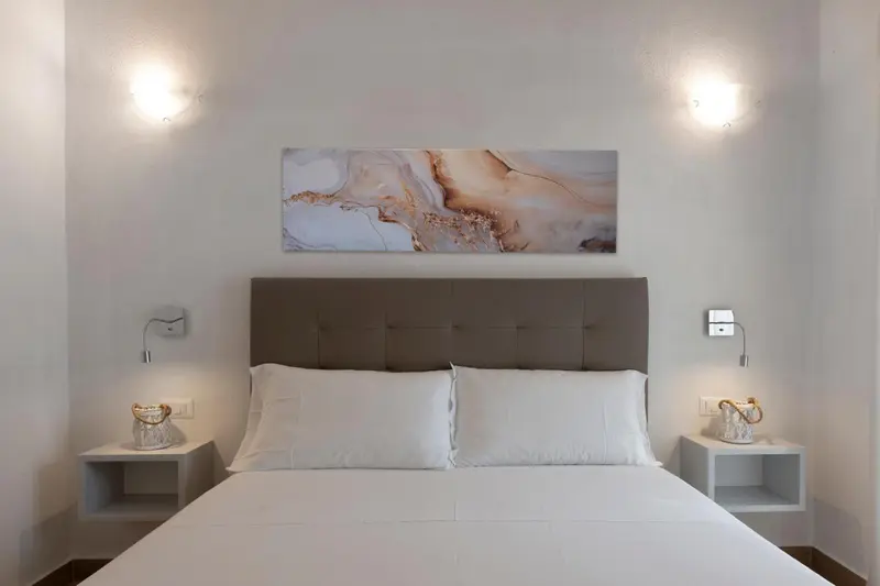 Une chambre lumineuse avec un grand lit et une décoration murale abstraite.