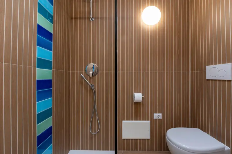 Une douche à l'italienne avec un mur décoratif en mosaïque bleue.