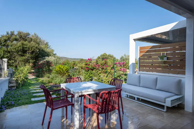 Terrasse aménagée avec salon et table à manger donnant sur un jardin fleuri.