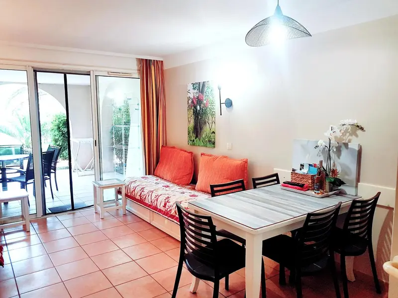 Espace de vie lumineux avec canapé, table et accès à une terrasse.