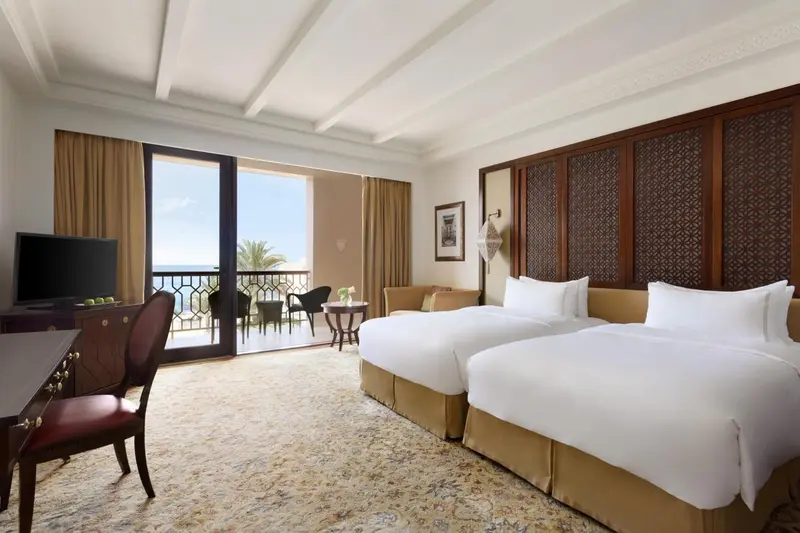 Chambre lumineuse avec deux lits simples et vue sur la mer.