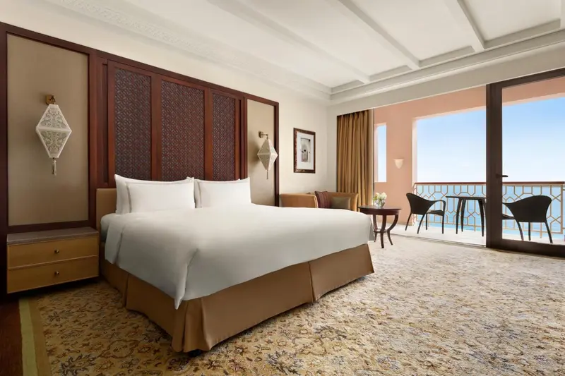 Chambre lumineuse avec un grand lit et un accès à une terrasse avec vue sur la mer.