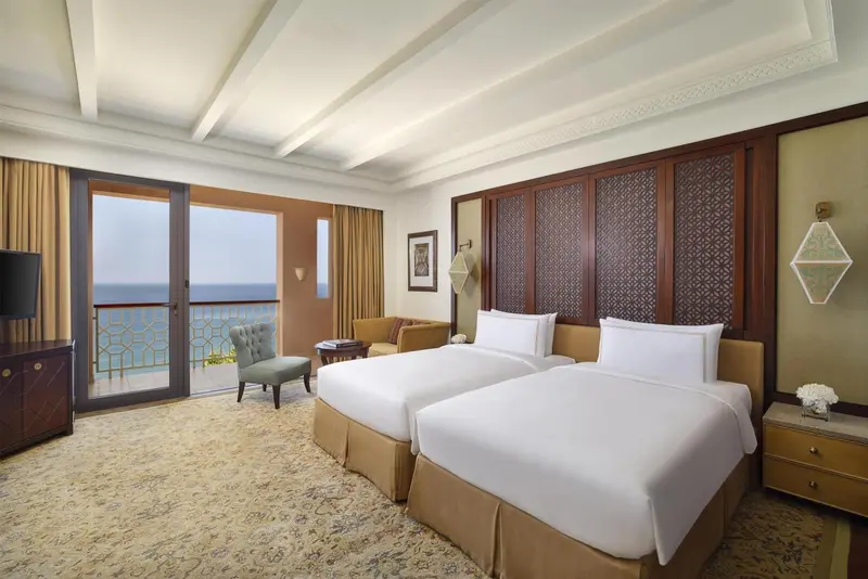 Chambre lumineuse avec deux lits simples et vue sur la mer.