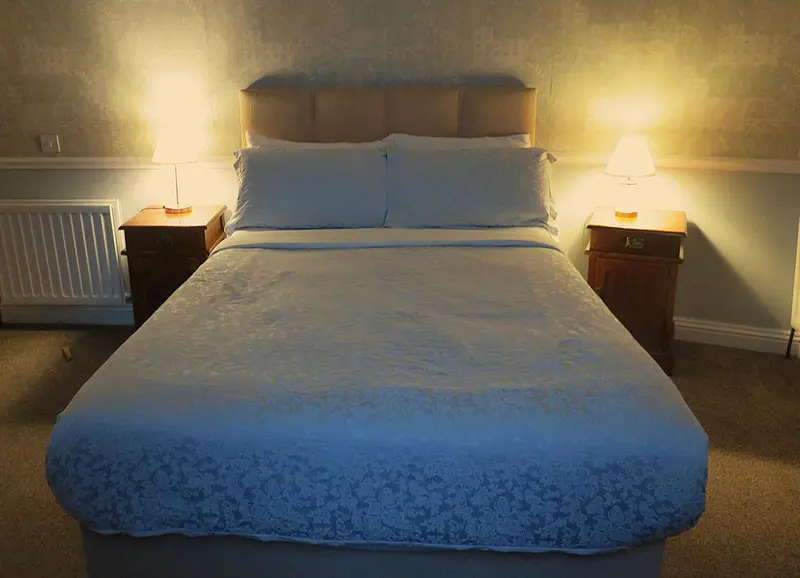 Une chambre lumineuse avec un grand lit recouvert d'une courtepointe blanche.