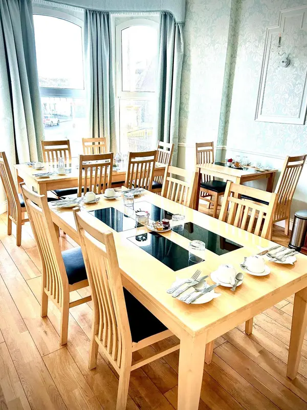 Une salle lumineuse avec des tables dressées pour le repas.
