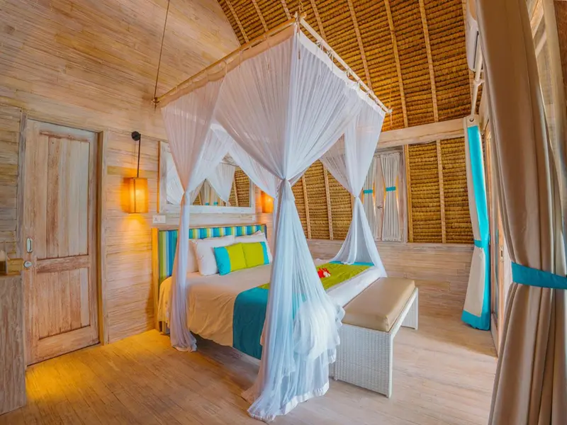Une chambre lumineuse avec un lit à baldaquin et une décoration tropicale.