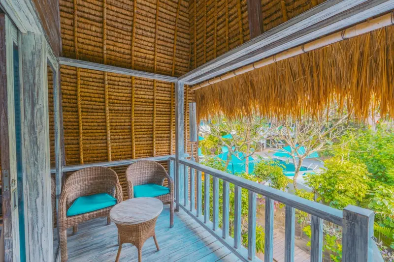 Terrasse avec mobilier en rotin donnant sur une piscine turquoise.