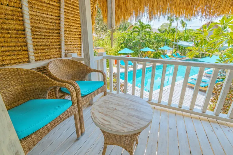 Terrasse aménagée avec mobilier en rotin donnant sur une piscine turquoise.