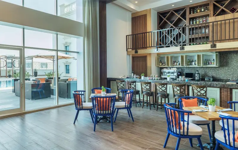 Une salle lumineuse avec un bar et des tables à manger près de grandes fenêtres.