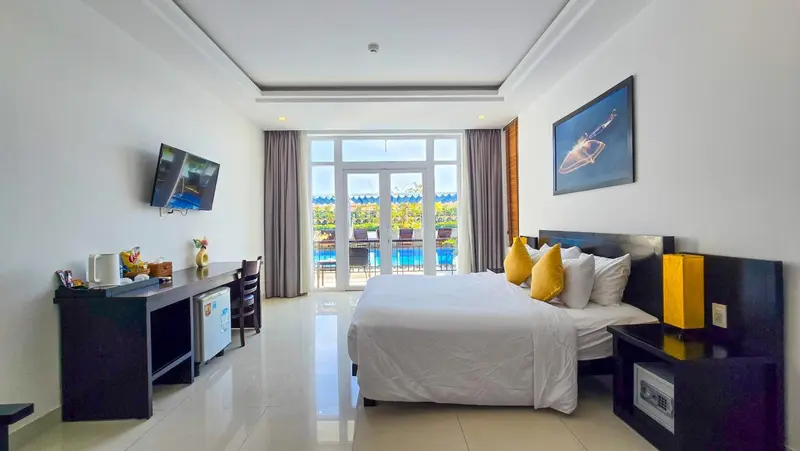 Une chambre lumineuse avec un grand lit et un accès à une piscine.