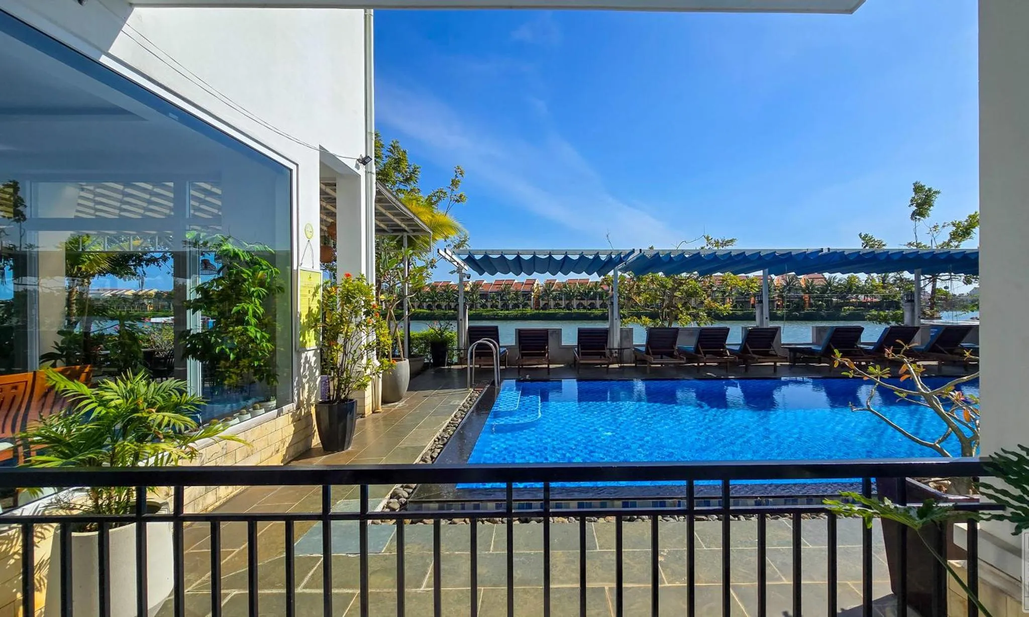 Une piscine rectangulaire avec des transats et une pergola en bord de mer.