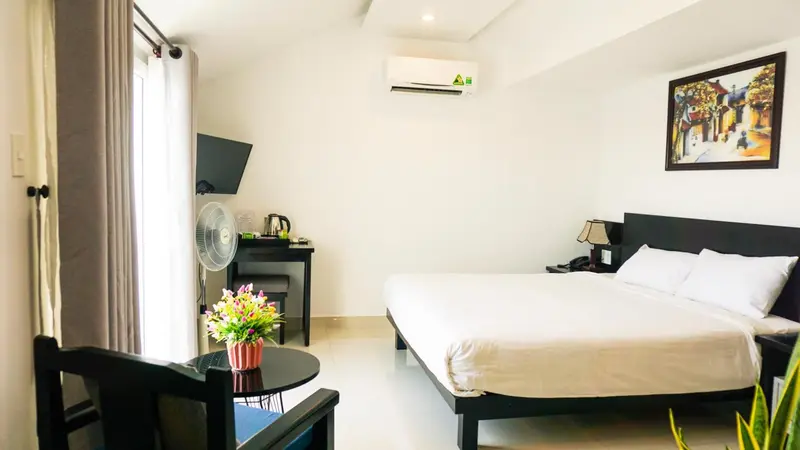 Une chambre lumineuse avec un lit double et un coin salon.