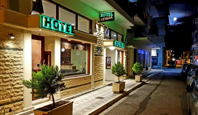 Façade d'un hôtel illuminée la nuit avec des plantes en pot.